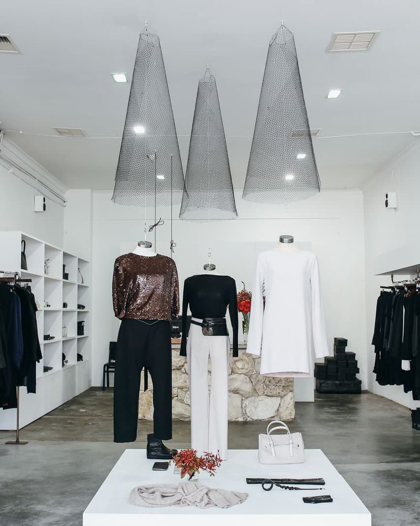 Minimal fashion boutique with garments lit by sculptural pendant lights