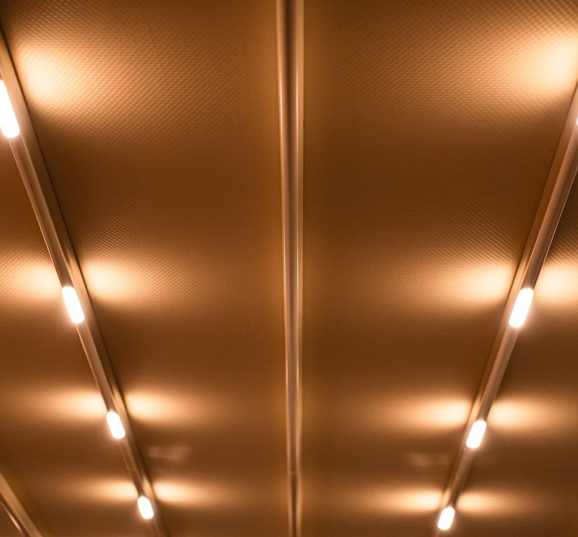 Warm linear LED profiles running along a copper-toned architectural ceiling